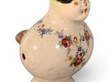 un petit vase orné d'une femme, posé sur un fond blanc