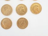 several gold coins are arranged in a row on a white surface