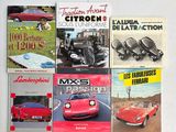 plusieurs livres posés sur une table blanche, avec une voiture rouge et une voiture rouge