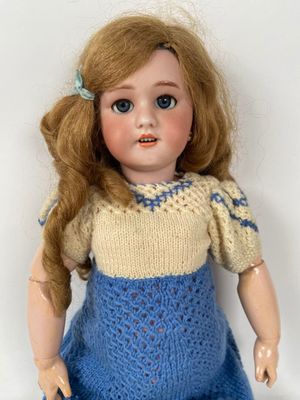 a doll that is wearing a blue dress and a yellow sweater