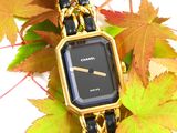 a black and gold watch sitting on a gold chain