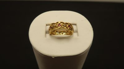 a close up of a gold ring with a red stone in it