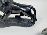 a statue of a lion on a rock next to a vase