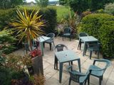 tables and chairs on a patio with a view of a green field