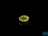 a close up of a yellow and green gemstone on a black surface