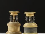 paire de bougeoirs anciens en laiton ornés de figurines sur des socles