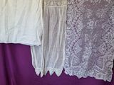 two white dresses hanging on a purple curtain in a room