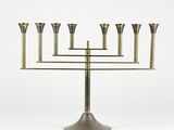a brass menorat with five candles on a stand