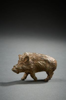 a small bronze figurine of a boar on a gray surface