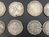 six silver coins of various sizes and shapes on a black surface