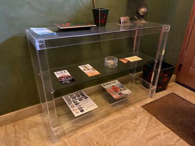 une étagère en verre sur laquelle sont posés des magazines, dans une pièce