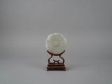 une sculpture en jade blanc représentant une fleur, posée sur un socle en bois