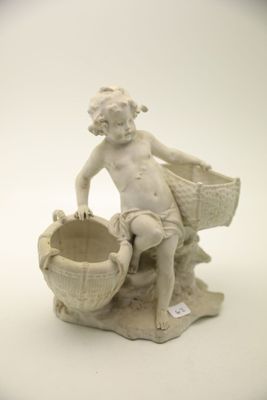 une statue représentant un garçon assis sur un rocher, tenant un panier