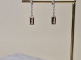 une paire de boucles d'oreilles posée sur un support posé sur une table