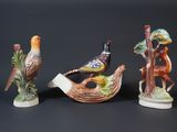 three figurines of birds and a bird on a branch
