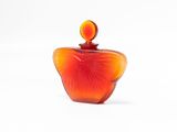 an orange glass perfume bottle with a red top sitting on a white surface