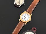 three different watches on a black surface with a watch in the foreground