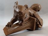 sculpture of a squirrel sitting on a piece of wood on a white background