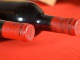 two bottles of wine sitting on a red table cloth