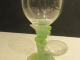 a green wine glass sitting on a table next to a black wall