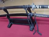 two samurai swords on a stand on a table