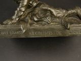 bronze statue of a boy laying on a book with a dog