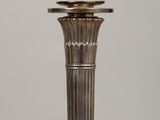 an antique silver plated candle holder sitting on top of a wooden table