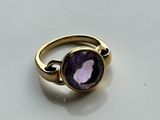 a close up of a ring with a purple stone in it