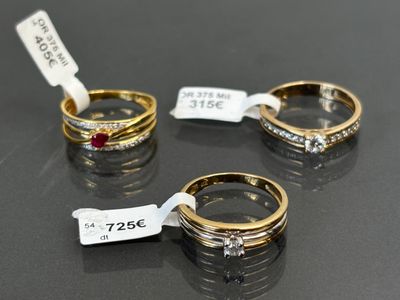 three gold rings with diamonds and a price tag on a table