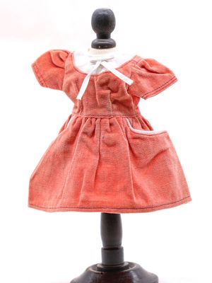 une poupée vêtue d'une robe rouge, posée sur un socle noir