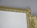 a mirror with a gold frame hanging on the wall