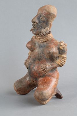 une vieille figurine représentant un homme assis sur un tabouret