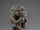 a small statue of a monkey holding a piece of wood