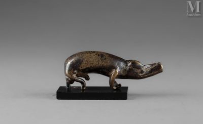 une figurine en bronze représentant un cochon, posée sur un socle noir