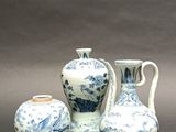 three blue and white vases and a vase on a table