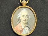 Une vieille photo représentant un homme vêtu d'un manteau rouge est exposée dans un cadre doré.