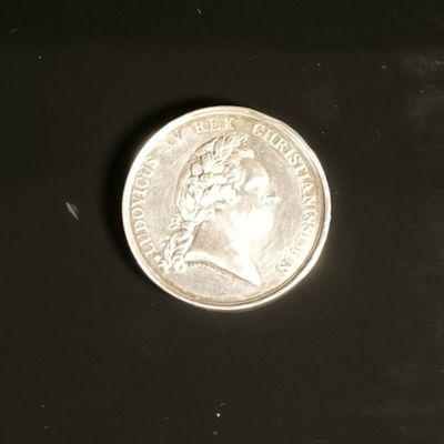 a close up of a silver coin on a black surface