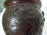 un vase marron orné d'un oiseau, posé sur une table