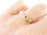 a woman ' s hand holding a ring with a green stone on it