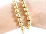 gold beaded bracelets on a woman ' s arm