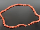 a necklace made of coral coral beads on a black surface