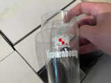 une personne tenant un verre sur lequel figure une croix rouge