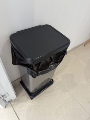 une poubelle posée par terre à côté d'une porte