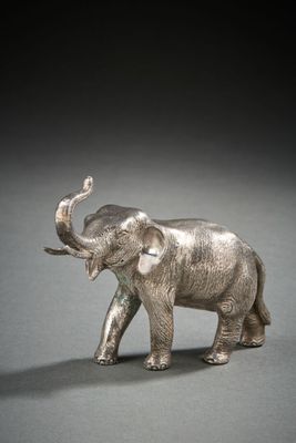 figurine d'éléphant en argent posée sur une surface grise avec un fond noir