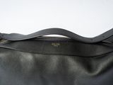 the large black bag is sitting on a white surface