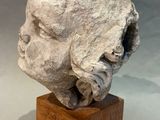 an image of a sculpture of a man ' s head on a wooden base