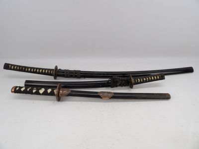 deux sabres de samouraï, l'un noir et l'autre doré, posés sur une surface blanche