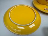 a yellow cup and saucer sitting on a white table