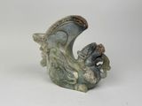 une petite statue de dragon posée sur une surface blanche