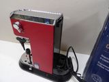 a red coffee maker sitting on a counter next to a blue box